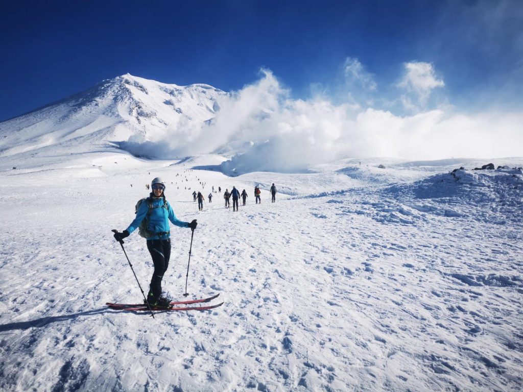 Una esquiadora posa en Asahidake frente a la cima del volcán y las fumarolas que salen de él. Isla de Hokkaido, Japón.