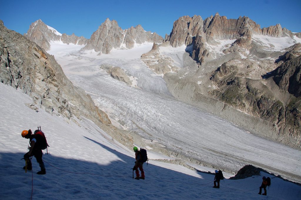 Grupo de alpinistas encordados y utilizando crampones en los Alpes